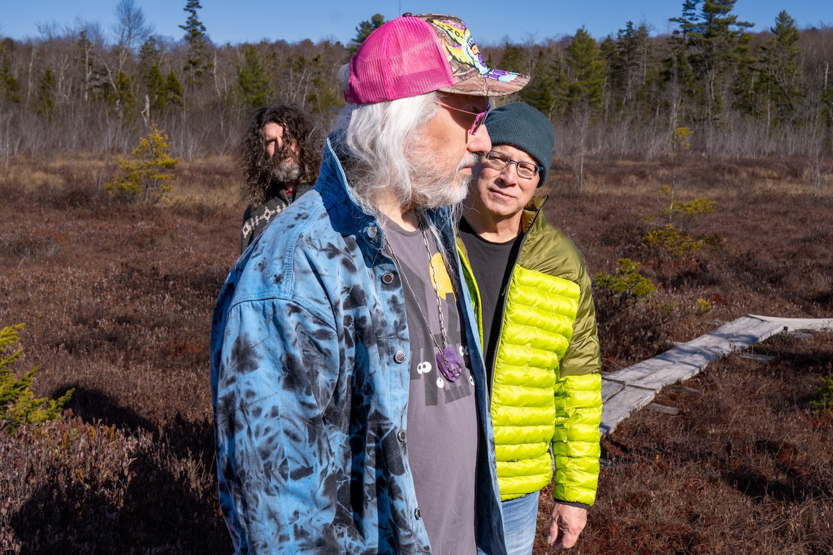 Alternative rock band Dinosaur Jr. posing outdoors in a grassy natural landscape.